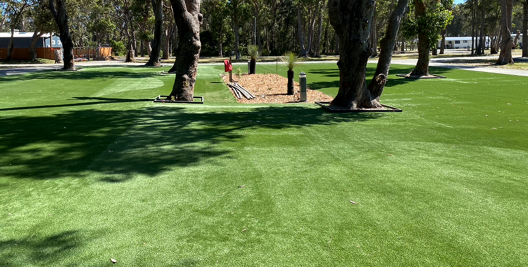 Newly laid turf with garden beds and trees spotted throughout